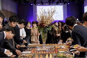 立食パーティーで料理を取る社員たち