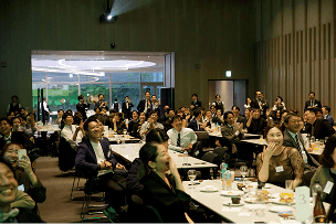 会場で着席してプレゼンを見る社員たち